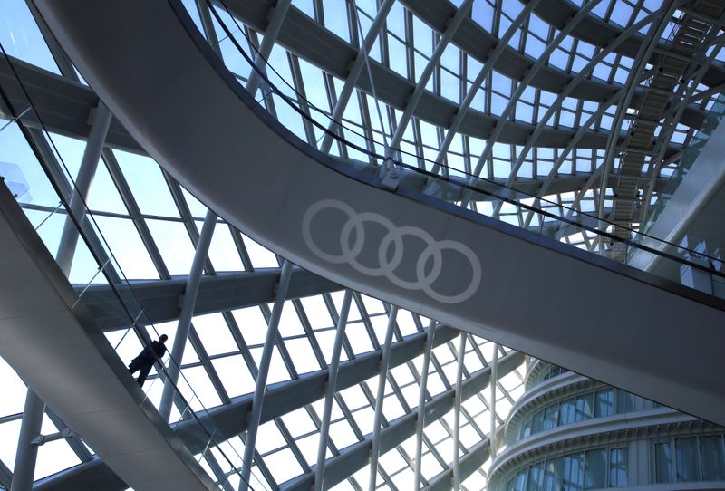 A man walks next to an Audi logo during the