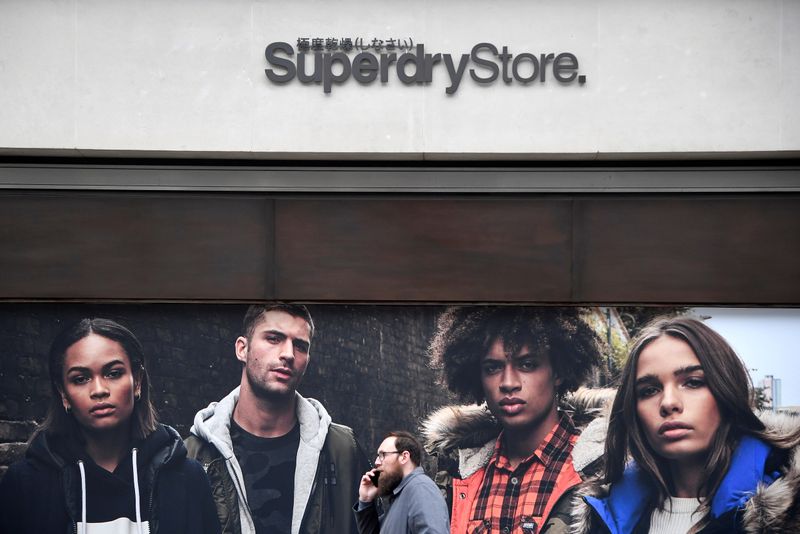 A man walks past a window display at a Superdry