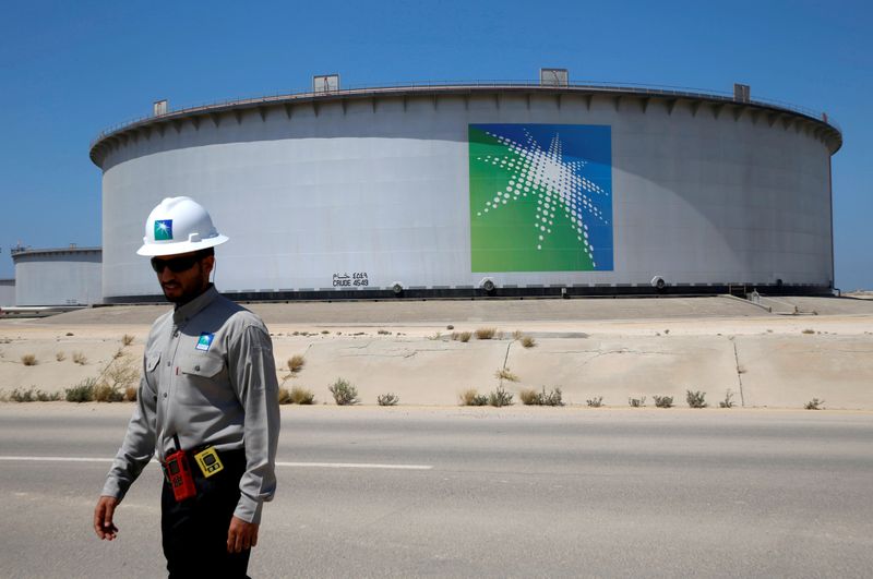 FILE PHOTO: An Aramco employee walks near an oil tank