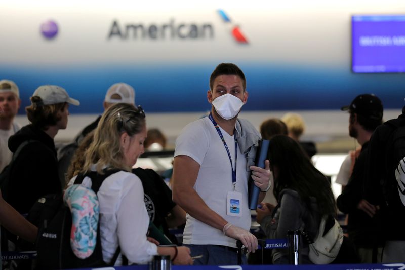 FILE PHOTO: A passenger wearing a mask waits in line