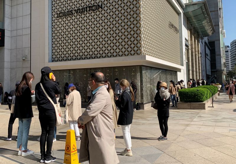 People queue to enter the Chanel boutique at a department