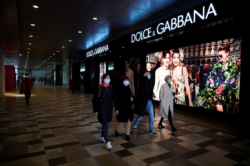 People wearing face masks walk past a Dolce & Gabbana