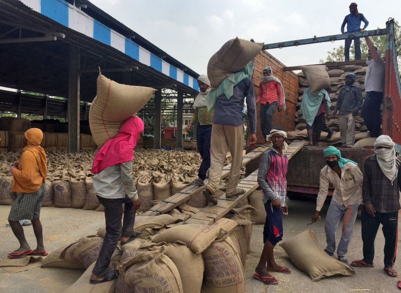 Workers load sacks of wheat onto a supply truck at