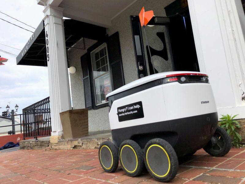 A Starship delivery robot waits outside a bar for orders