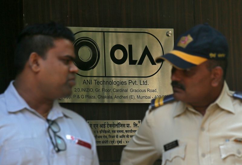 A policeman speaks to an Ola employee outside its office