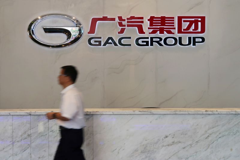 Man walks past the logo of Chinese automobile maker GAC