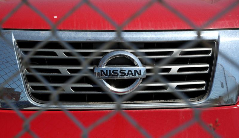 The logo of Nissan is seen on a car through