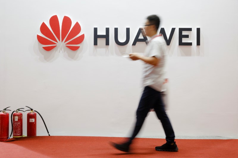 A man walks past a Huawei company logo at the