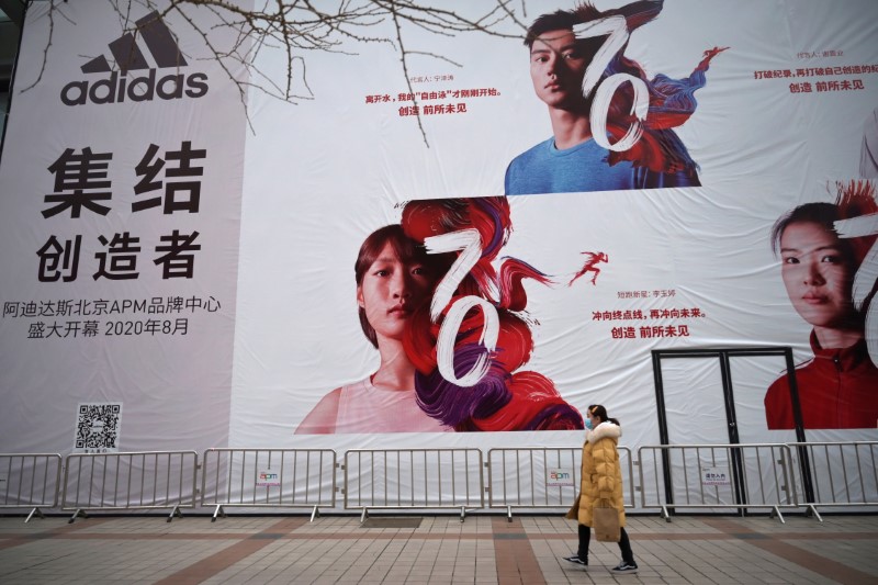 A woman wearing a face mask walks past a banner