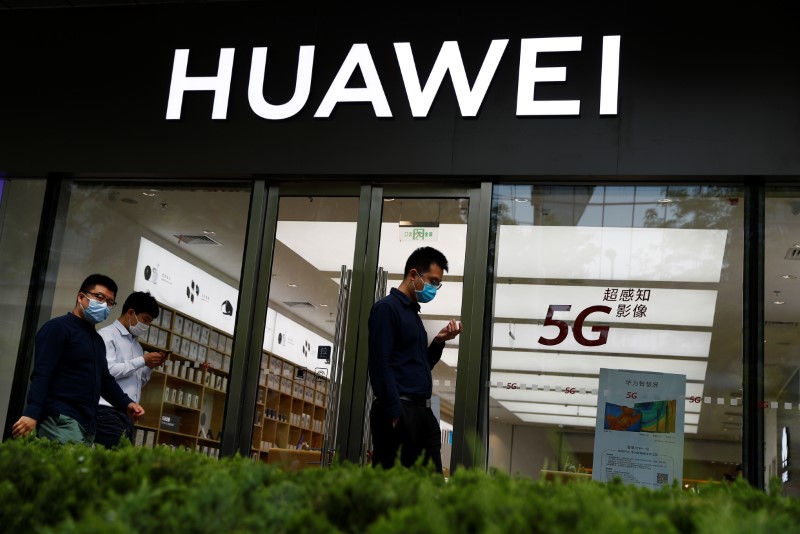 People walk past a Huawei shop, amid an outbreak of