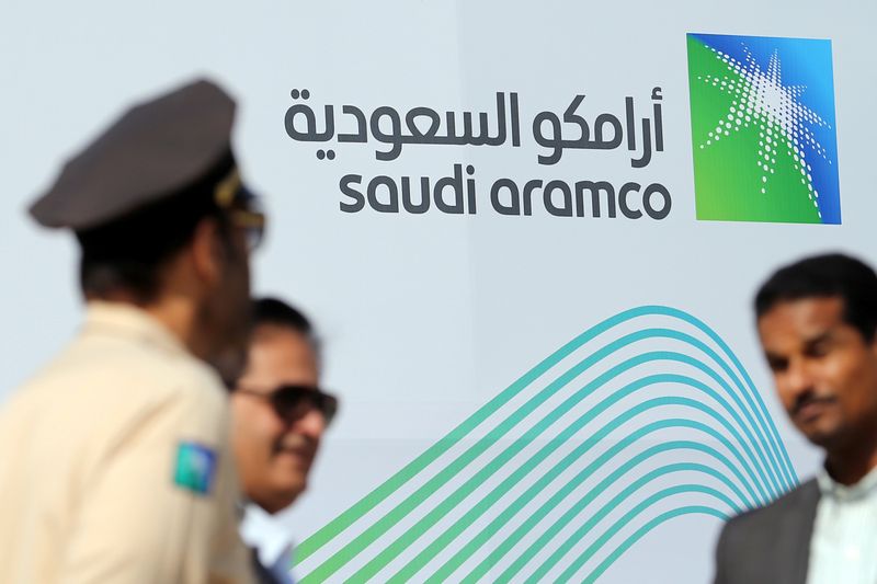 Logo of Aramco is seen as security personnel stand before