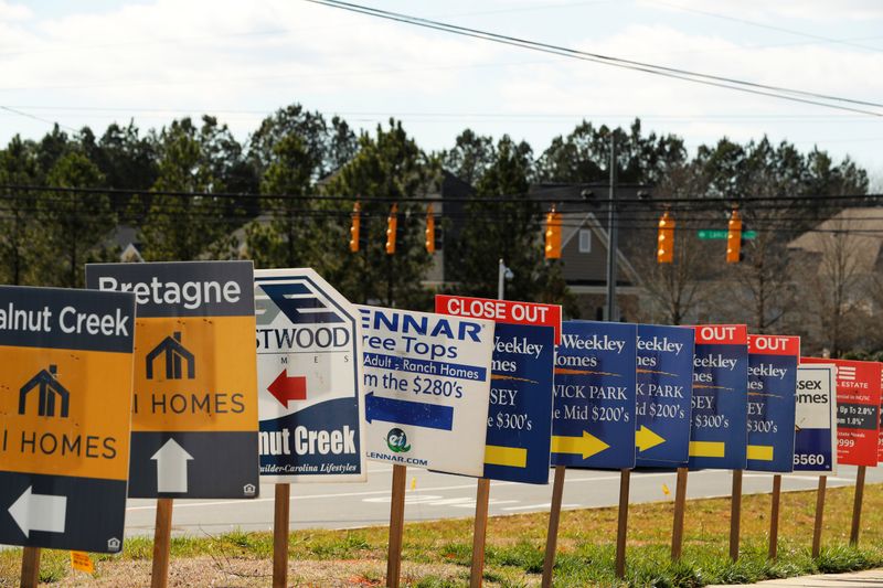 Real estate signs advertise new homes for sale in multiple