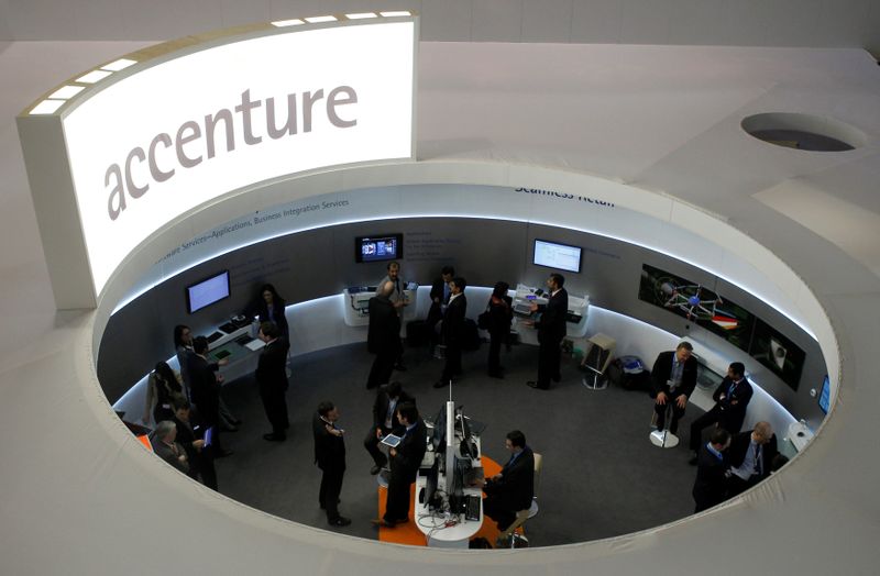 Visitors look at devices at Accenture stand at the Mobile