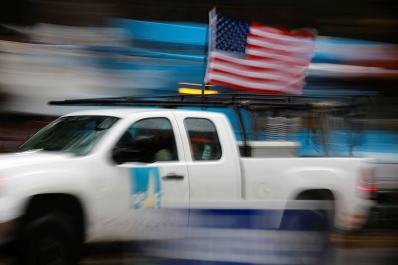A PG&E truck carrying an American Flag drives past PG&E