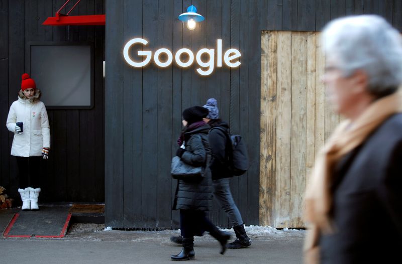 FILE PHOTO: People walk past the logo of Google in