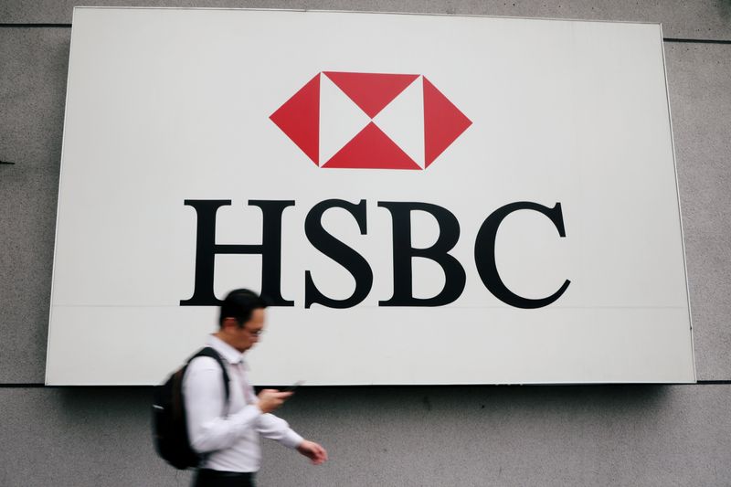 FILE PHOTO: A man walks past a logo of HSBC
