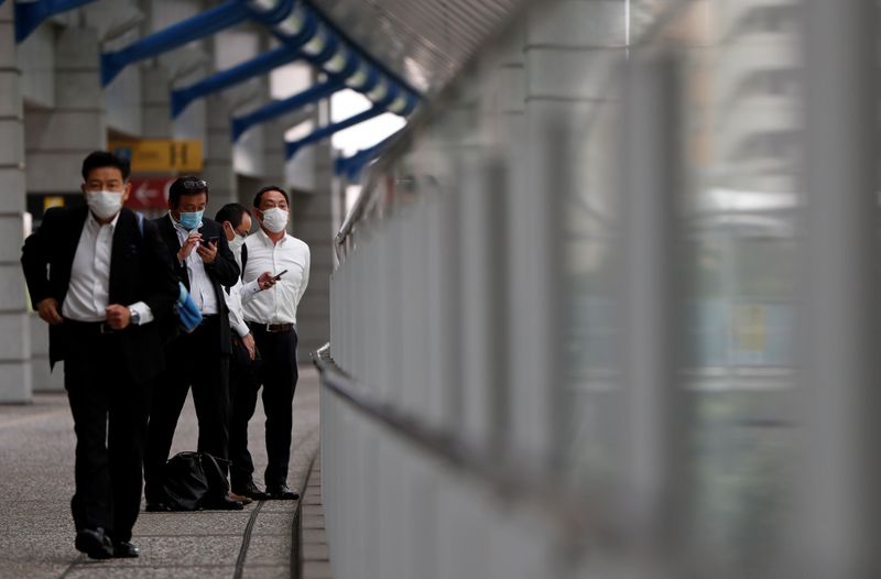 Businessmen wearing protective face masks are seen on a pedestrian