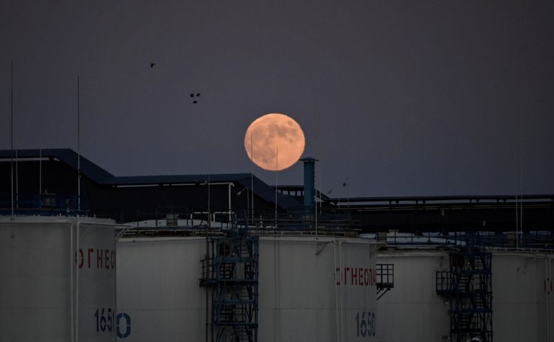 FILE PHOTO: The moon rises behind oil storage tanks in