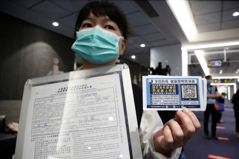 An airport staff holds up information boards regarding passenger health