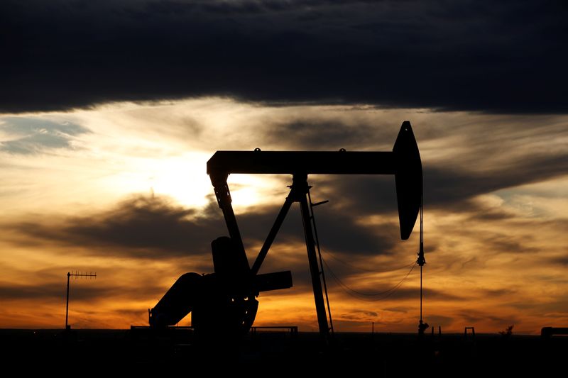 The sun sets behind a crude oil pump jack on
