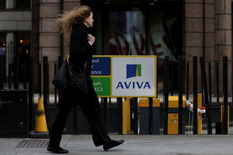 A pedestrians walks past the Aviva logo outside the company
