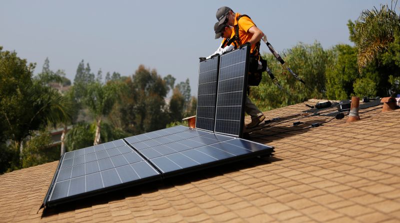Vivint Solar technicians install solar panels on the roof of