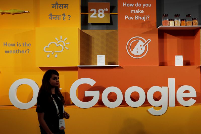 A woman walks past the logo of Google during an