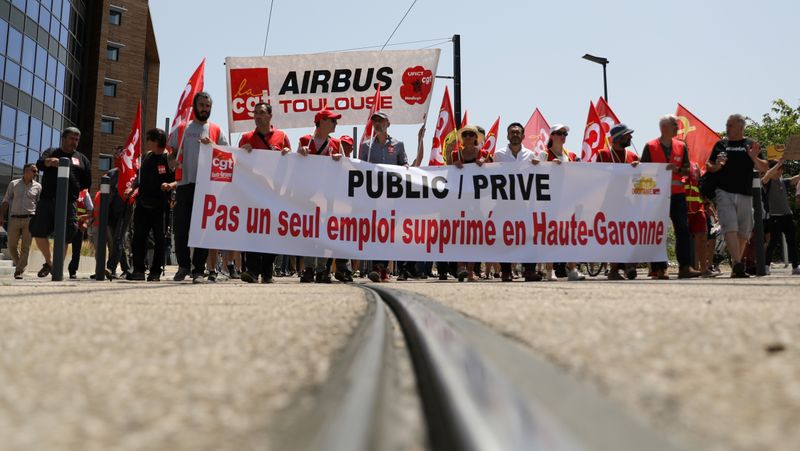 Employees of Airbus hold a banner reading “Not a single