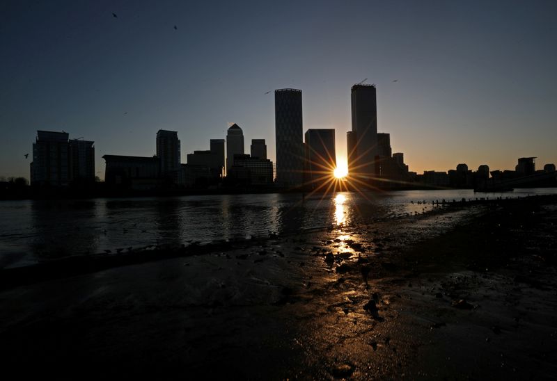 FILE PHOTO: The sun rises behind the Canary Wharf financial