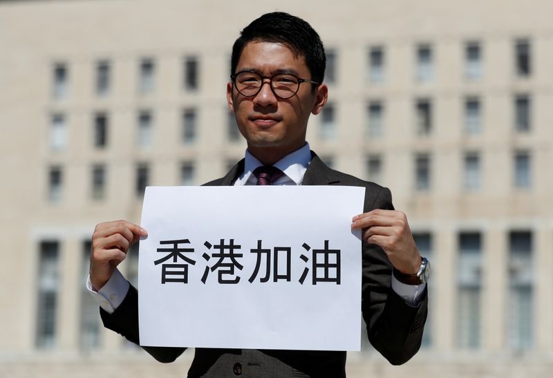 Exiled Hong Kong pro-democracy activist Nathan Law holds a placard