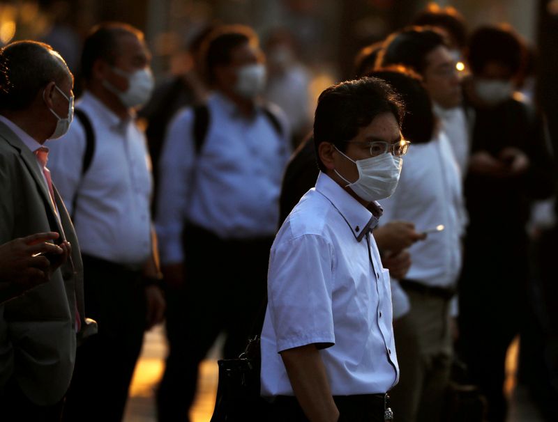 FILE PHOTO: Office workers wearing protective face masks walk to