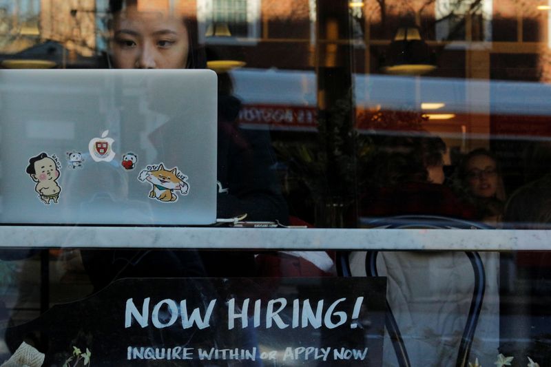 A “Now Hiring” sign sits in the window of Tatte