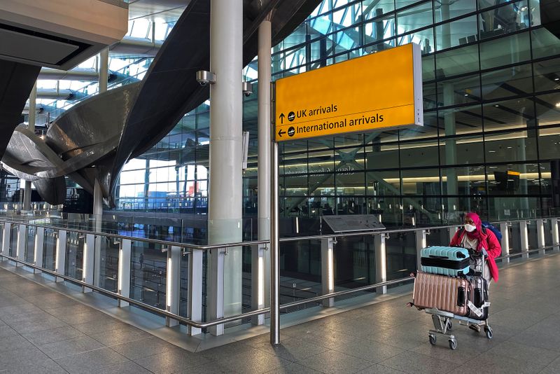 FILE PHOTO: An air passenger pushes luggage at Heathrow Airport