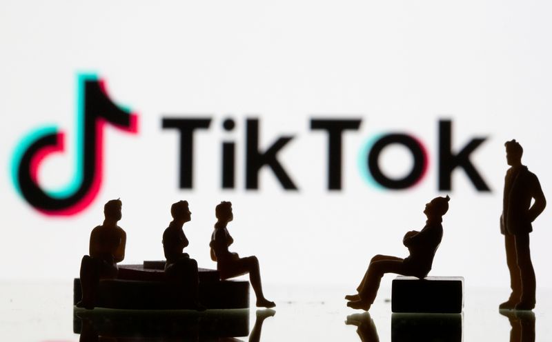 Small toy figures are seen in front of a Tiktok