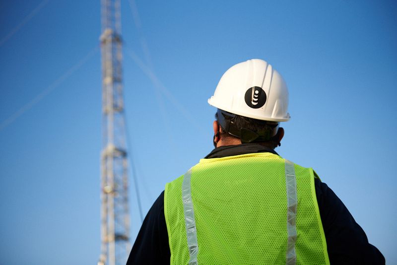 A worker stands in front of a mobile tower in
