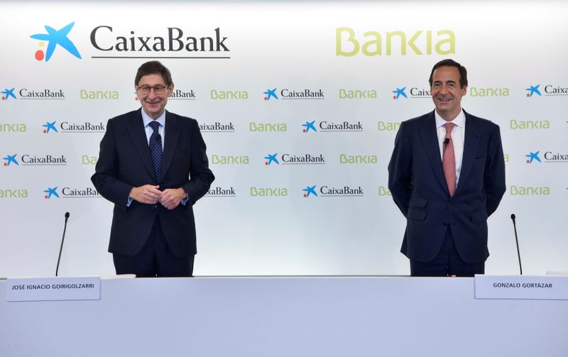 Caixabank’s Gortazar and Bankia’s Goirigolzarri stand before their joint news