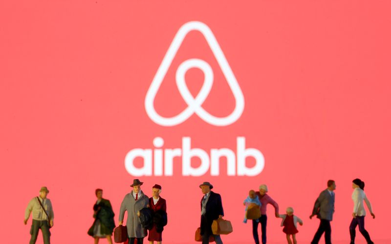 Small toy figures are seen in front of diplayed Airbnb