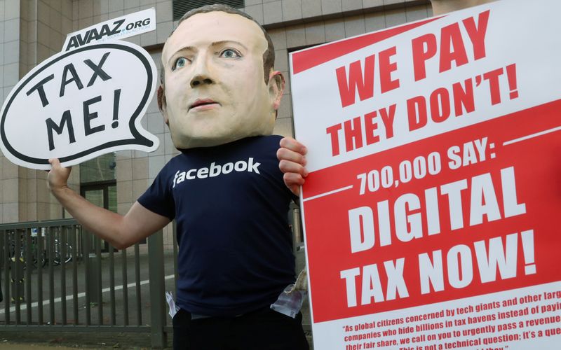 FILE PHOTO: An activist wearing a mask depicting Facebook’s CEO