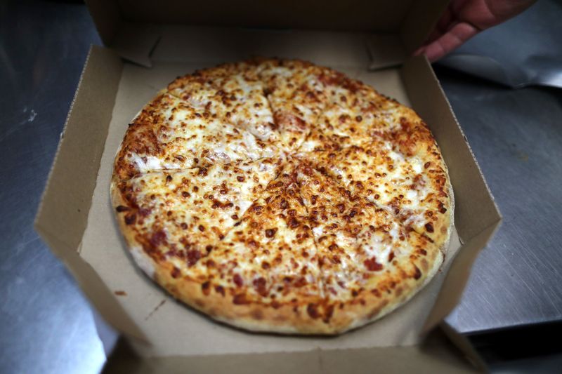 A pizza comes out of the oven at Domino’s Pizza