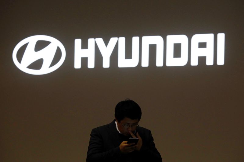 A man walks past the logo of Hyundai Motor during