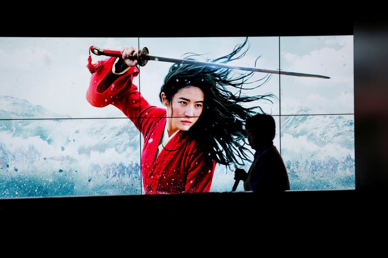 FILE PHOTO: Cleaner walks past screens promoting Disney’s movie “Mulan”