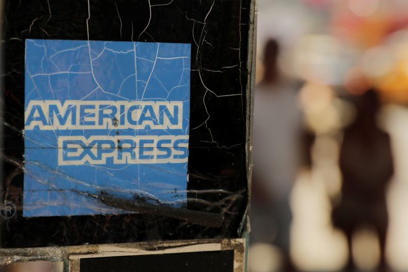 Pedestrians walk past an American Express sign in New York