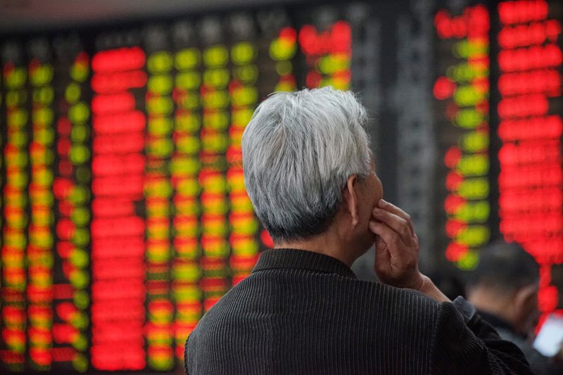 An investor looks at an electronic board showing stock information