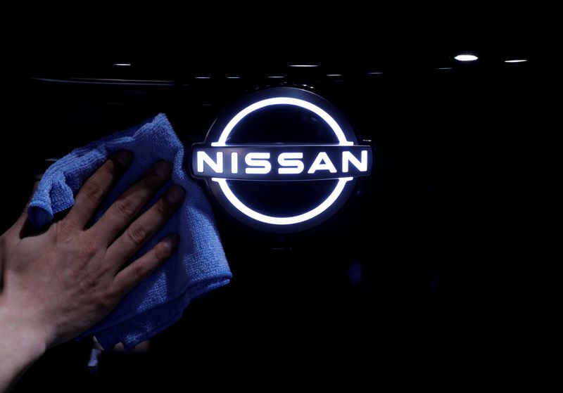 FILE PHOTO: A man wipes the brand logo of Nissan
