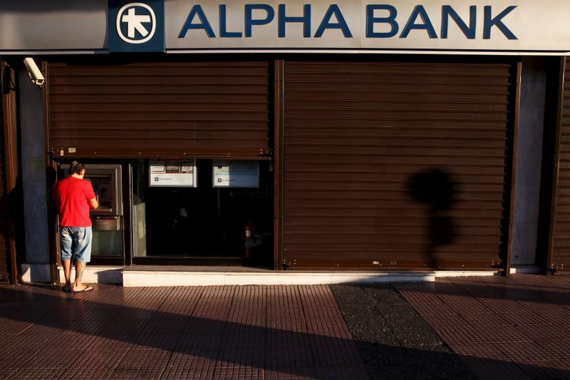 FILE PHOTO: A man withdraws money at an Alpha Bank