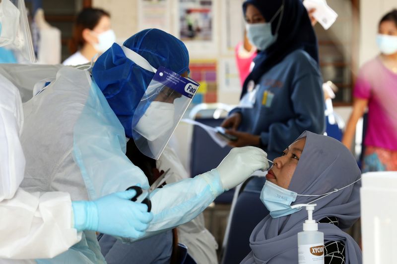 A medical worker collects a swab sample from a Top