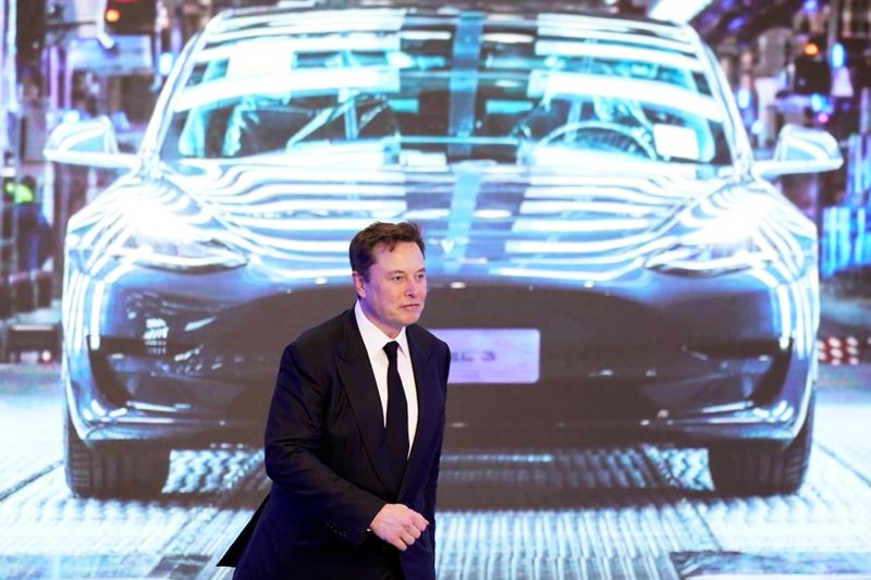 Tesla Inc CEO Elon Musk walks next to a screen