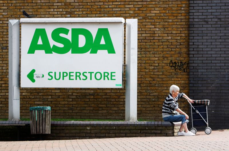 FILE PHOTO: A shopper sits by an Asda superstore sign