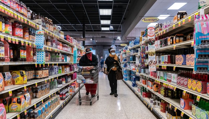 Shoppers browse in a supermarket while wearing masks in St