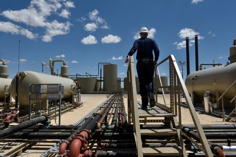 Lease Operator Jeremy Jay walks through an oil production facility